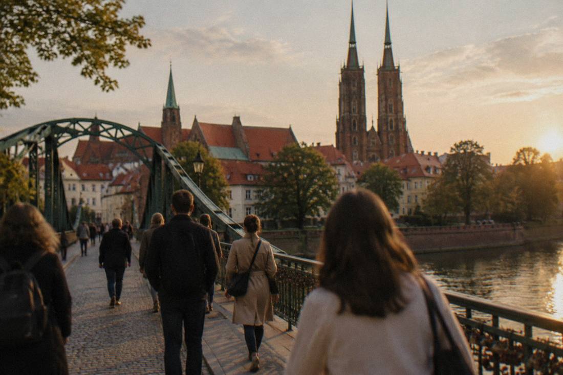 People crossing a historic bridge over the Odra river toward church towers on Cathedral Island in Wroclaw