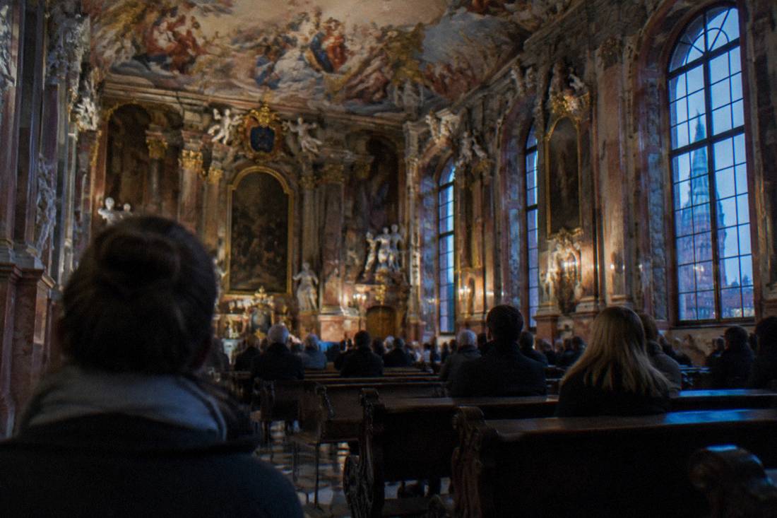 Interior of a grand baroque ceremonial hall with frescoed ceiling and rows of benches