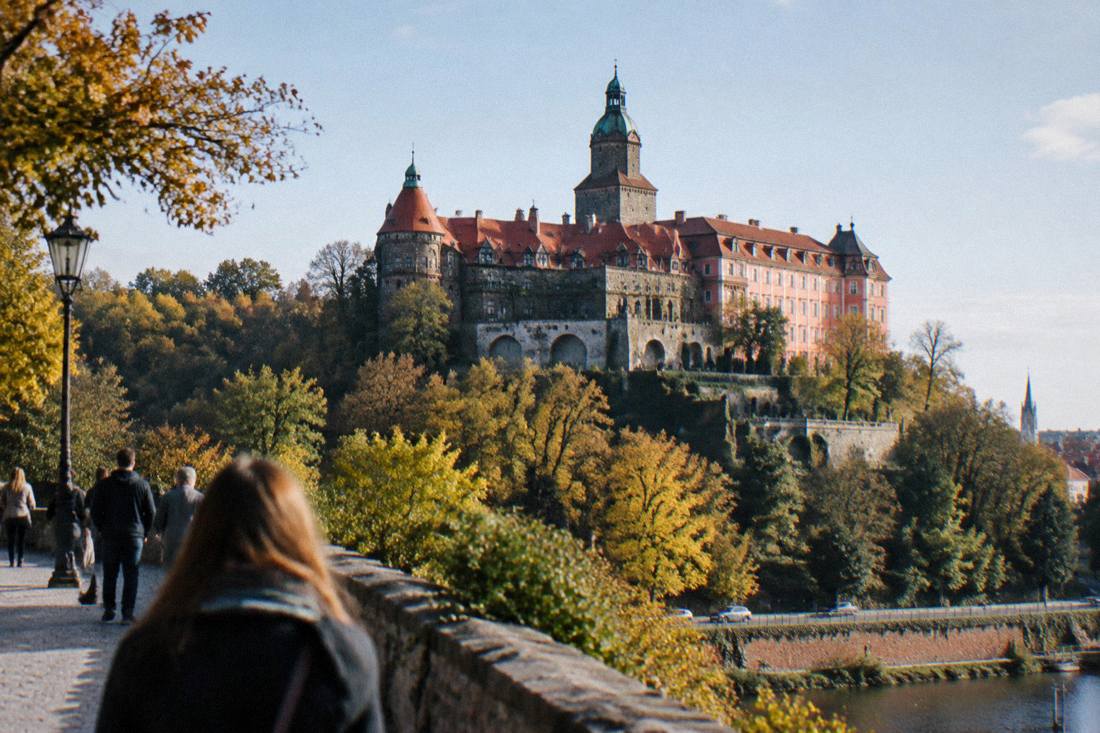 Large hilltop castle with towers and terraces above wooded hills in Lower Silesia