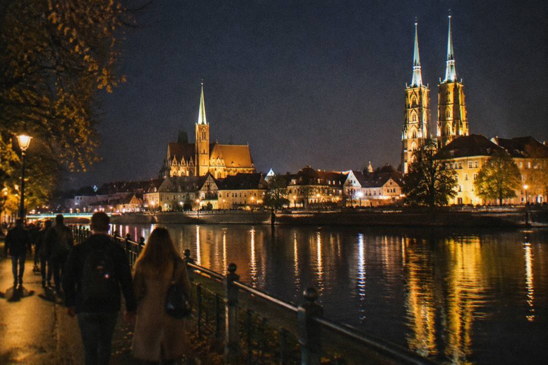 A night view of illuminated buildings beside the water in central Wroclaw