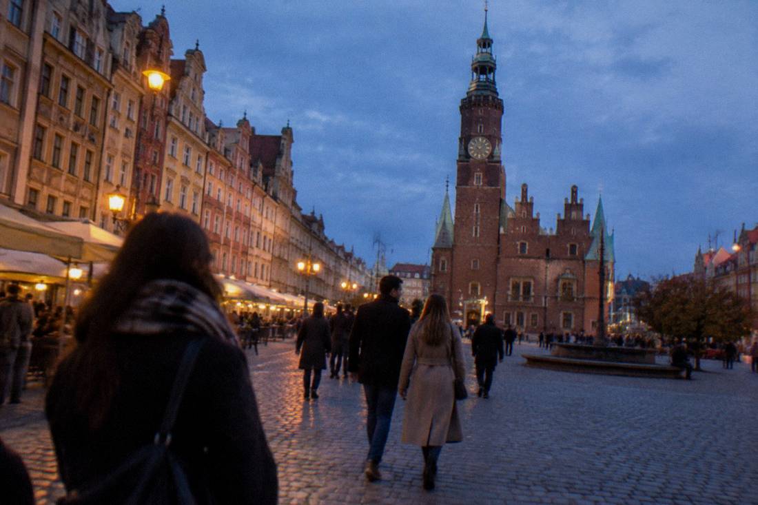 People strolling across a Wroclaw square with historic facades in warm evening light