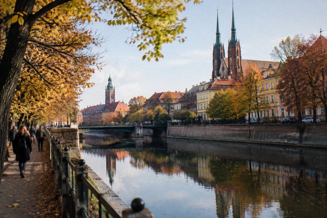 Autumn leaves on trees beside a Wroclaw canal with reflections in the still water