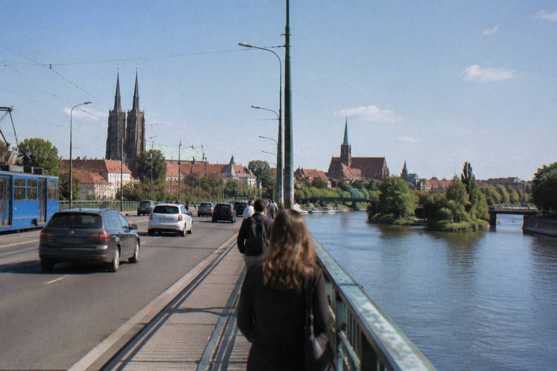 Traffic crossing a bridge over the Odra river in Wroclaw with church towers in the background