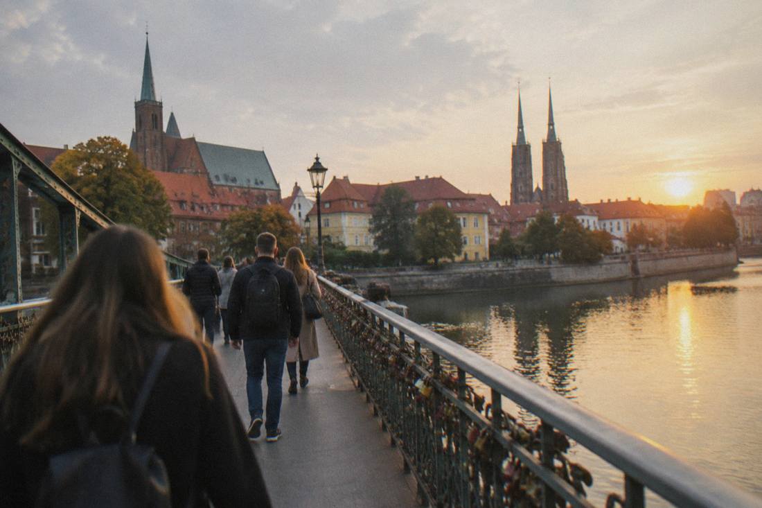 Visitors walking across a bridge between Wroclaw's river islands at golden hour