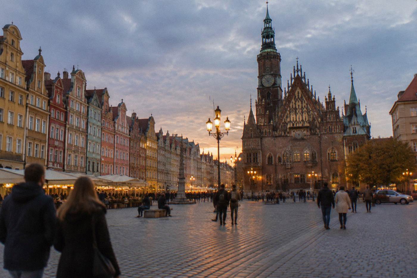 Wide view of Wroclaw Market Square with colorful townhouses and the Gothic town hall at dusk