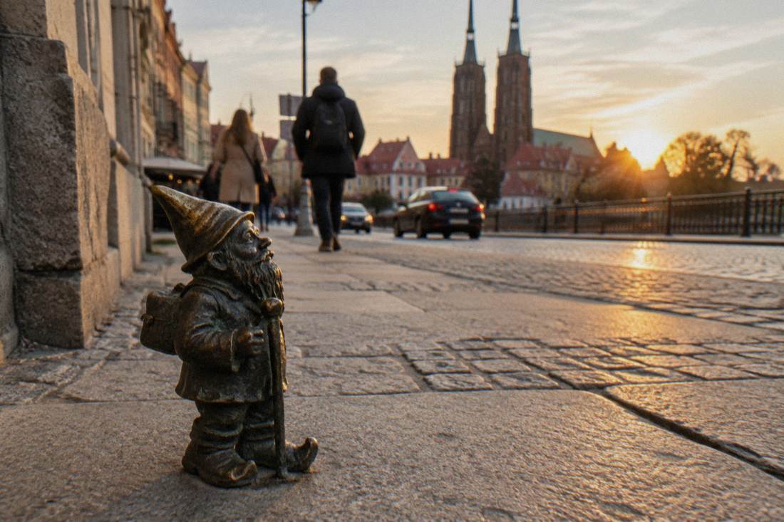 A small bronze dwarf statue standing on a Wroclaw sidewalk