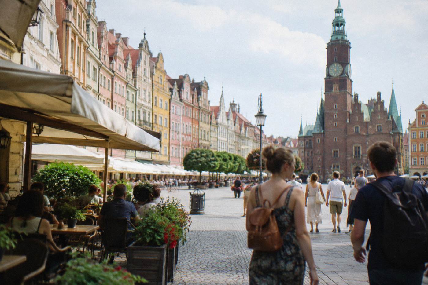 Wroclaw market square on a bright summer day with colorful townhouse facades and café tables in the shade