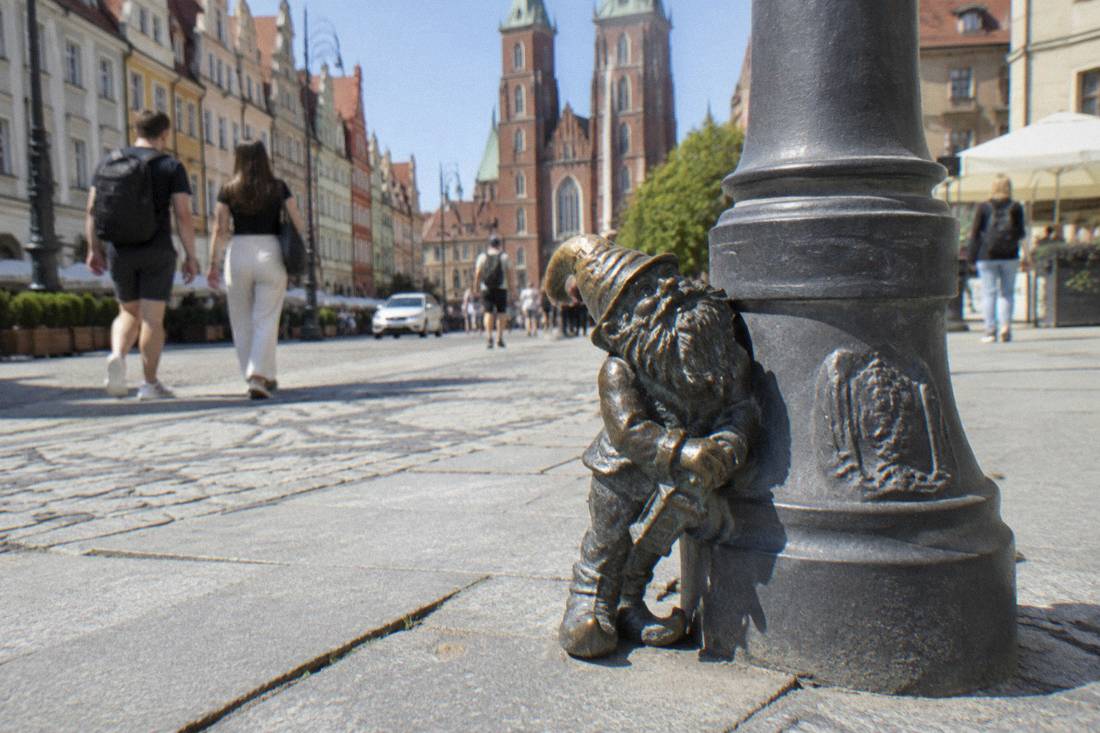 A small bronze dwarf statue at the base of a lamppost in central Wroclaw